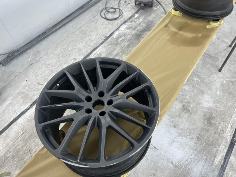 Grijze autovelg op werktafel in werkplaats.