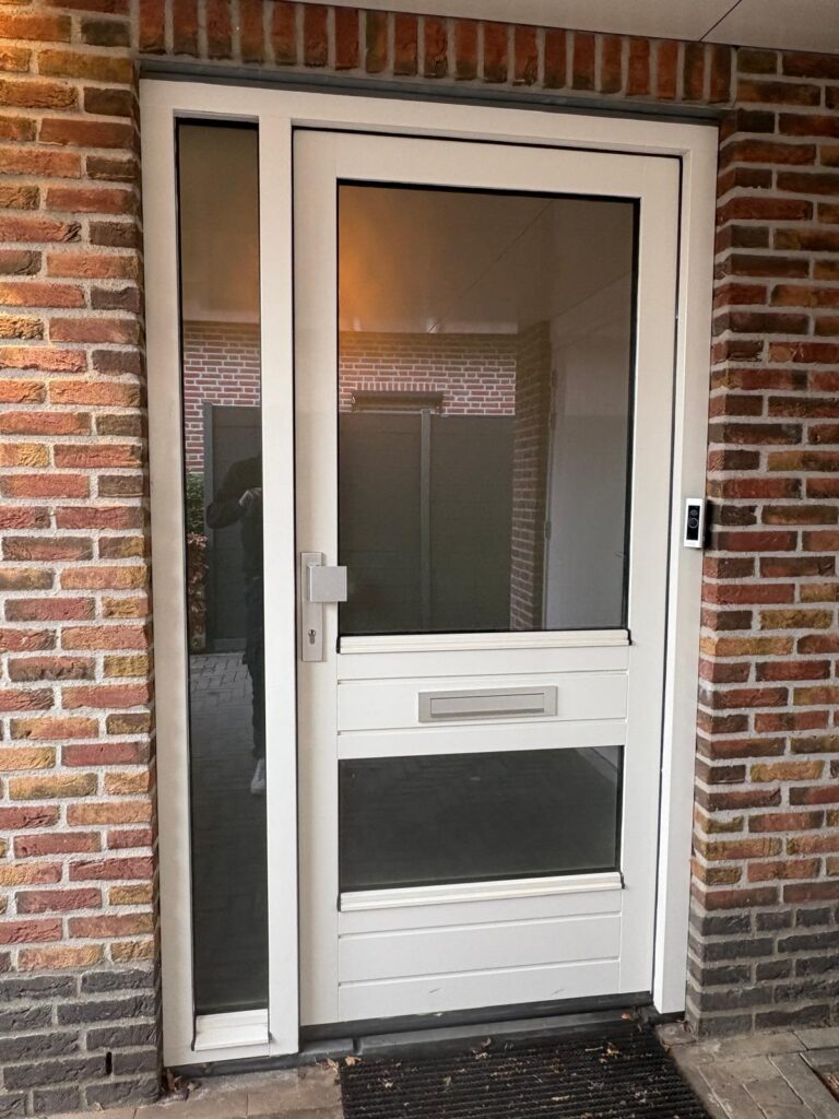 Witte voordeur met glas in bakstenen muur.