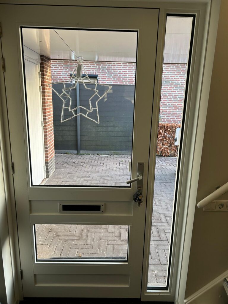 Witte deur met stervormige hangdecoratie, bakstenen muur.