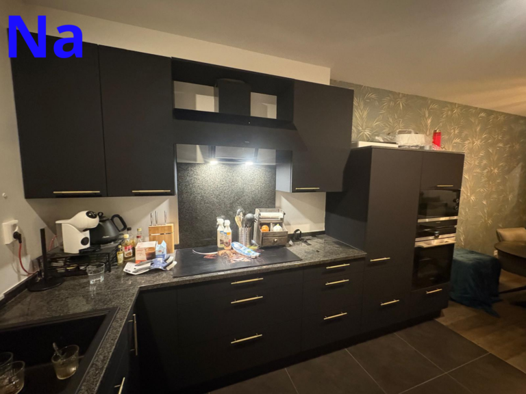Moderne zwarte keuken met apparaten en verlichting.