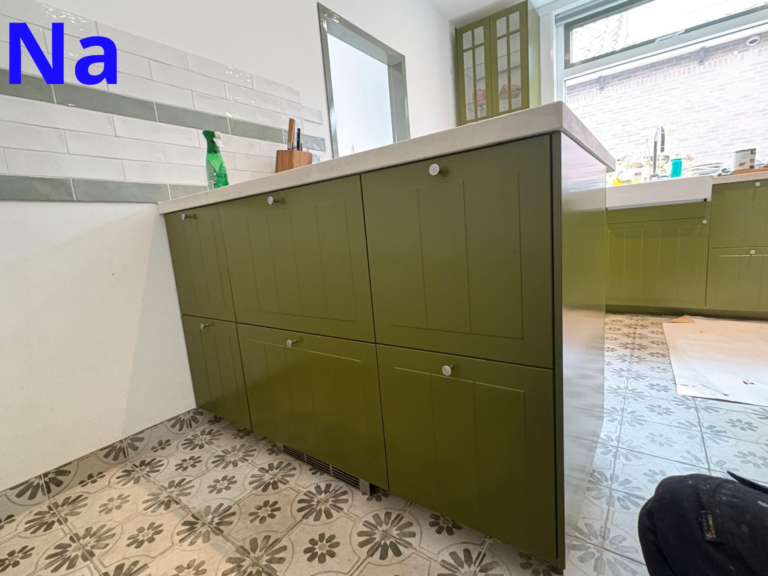 Moderne keuken met groene kasten en tegelvloer.