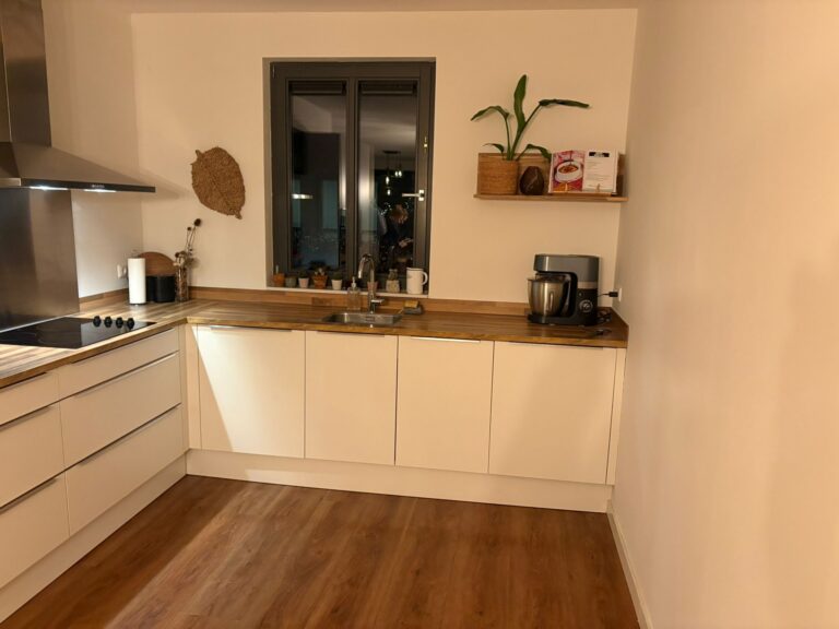 Moderne keuken met houten aanrecht en raam.
